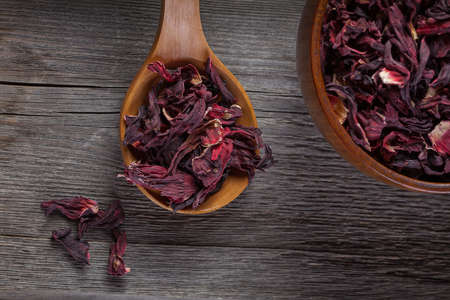 Bowl of aromatic Hibiscus tea with wooden spoon on wooden boardの写真素材