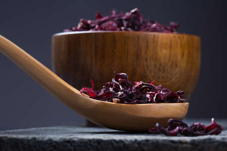 Bowl of aromatic Hibiscus tea with wooden spoon on wooden boardの写真素材