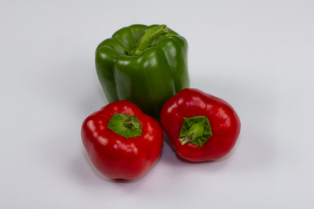 Two red and one green peppers are shot close-up on a white background. Red and green bell peppers are very tasty and healthy vegetables.の写真素材