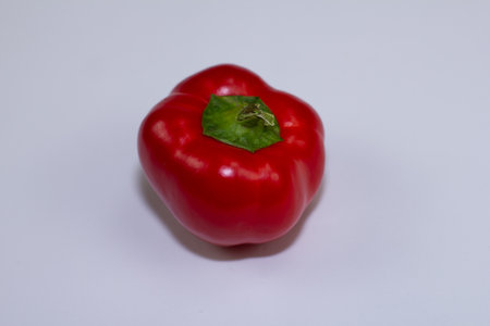 Fresh bell pepper lies on a white background. Juicy red pepper is good for the human body. Pepper with a shadow on the side lies on a white table. vegetables are very healthy and tastyの写真素材