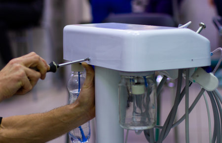 The master tightens the bolts with a screwdriver on the body of the medical oxygen apparatus. A...