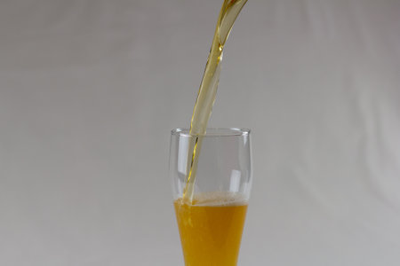 The beer flows in a beautiful stream into the glass. Golden beer with bubbles fills the glass. Isolated on white background.の写真素材