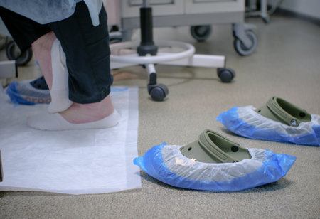 In the operating room, the doctor stands barefoot on the floor near the operating table. There are shoes nearby. The hard work of a surgeon. The concept of a surgeon standing barefoot.の写真素材