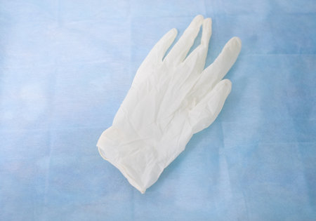 A taken off white latex glove lies on a blue background in khururgy. A sterile medical white glove...