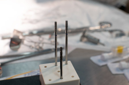 Drills for a surgical drill sit on a table surrounded by other surgical instruments. In the...