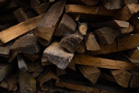 Stack of old chopped dry firewood under a canopy. Firewood stacked in a neat pile. Close-up firewood slices, where the woody pattern is clearly visible.の写真素材