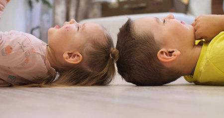 Brother and sister lie on the floor smiling head to head. Love and friendship between brother and sister. Cute and beautiful children at home. Kids home life concept.の写真素材