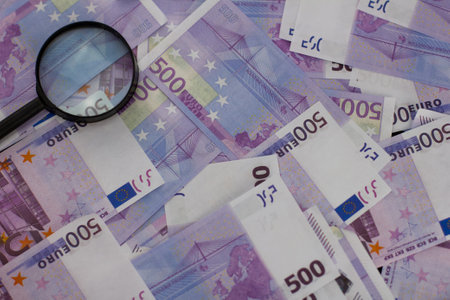Financial background. A pile of euro bills lies on the table. On top of the euro lies a loupe...