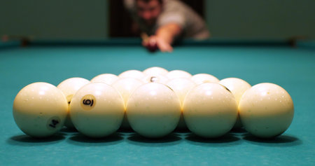 A man starts a game of billiards by breaking the balls with an accurate cue hit. The man takes aim...