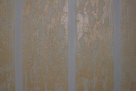 Beautiful decorative striped plaster of gold color on the wall. Background of golden plaster with a decorative pattern and a pronounced texture.の写真素材