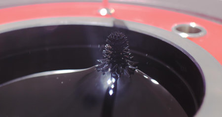 Experiment on the movement of a ferromagnetic black liquid under the action of a magnetic field. Ferrofluid takes on bizarre sharp shapes under the influence of a magnetic field.の写真素材