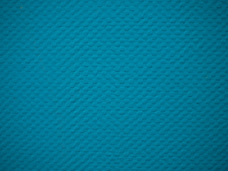 Textured background of a plasterboard wall that has been wallpapered for painting and painted blue....