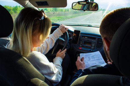 A driving instructor explains to a female student the rules for driving a car. A woman takes a driving test driving a car with an instructor. The concept of an auto law exam.の写真素材
