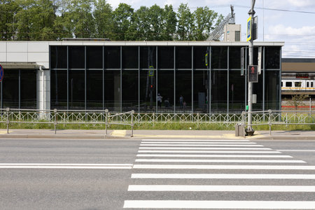 City empty pedestrian crossing through a wide highway. Striped empty pedestrian crossing against a mirrored building. On a summer day, an empty pedestrian crossing over a highway.の写真素材