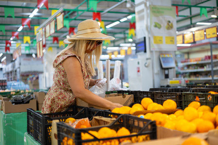 A woman at a farmers market chooses organic food for her family. In the vegetable section, a lovely woman chooses food for dinner. Healthy food concept.の写真素材