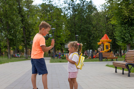 Brother and sister have fun and laugh in the park on the walking path in summer. Children walk in the park on a hot sunny summer day. Happy children walk in the park and play in summer.の写真素材