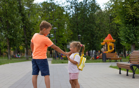 Brother and sister have fun and laugh in the park on the walking path in summer. Children walk in the park on a hot sunny summer day. Happy children walk in the park and play in summer.の写真素材