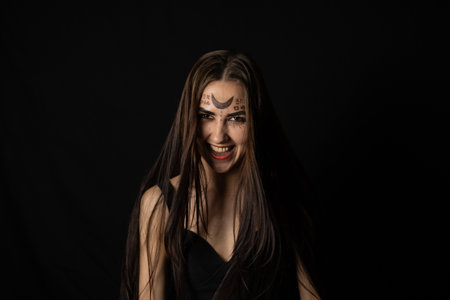 Evil laughing at the top of her voice, the witch looks into the camera on a black background in the...