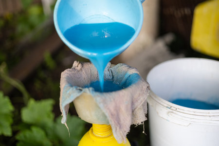 Using gauze in the garden, a woman strains fertilizer and pours it into a spray bottle. The gardener prepares a solution of minerals and fertilizers for treating plants.の写真素材