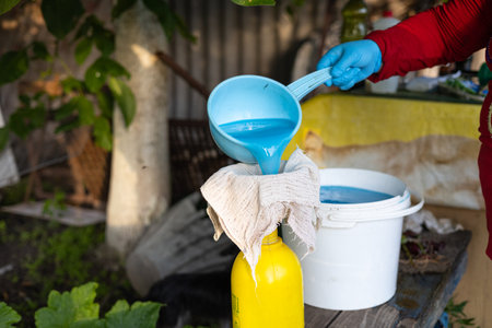 Using gauze in the garden, a woman strains fertilizer and pours it into a spray bottle. The gardener prepares a solution of minerals and fertilizers for treating plants.の写真素材