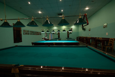 Empty billiard room with green tables illuminated by lamps. Beautiful game room for billiards...