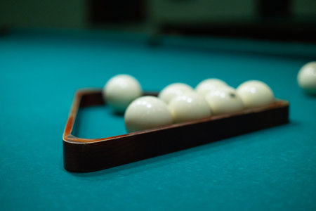 A mans hands stack billiard balls into a pyramid on a billiard table. A man collects balls into a billiard triangle to start a new game of billiards.の写真素材