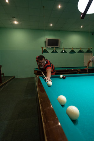 A group of people gathered in the billiard room to play and have fun. A group of friends plays...