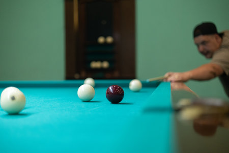 A man aims a cue at a billiard ball on a green table. A man hits a billiard ball and tries to pocket...