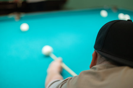 Cute man aiming a cue at a billiard ball. In the evening, a man relaxes and relaxes while playing...