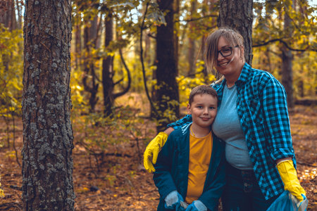 Mother and son eco activists collect garbage in the forest The family takes care of saving the forest from garbage. A woman teaches her child to take care of nature and clean up trash. Saving nature.の写真素材