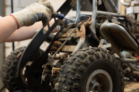 A male mechanic replaces a broken part in his sons ATV with a new one using tools. A man is...