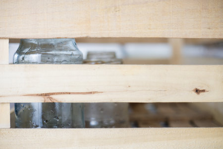 In the kitchen there is a wooden box with glass that needs to be recycled. Collecting glass waste into a box for recycling. A housewife in the kitchen was collecting old glass jars for recycling.の写真素材
