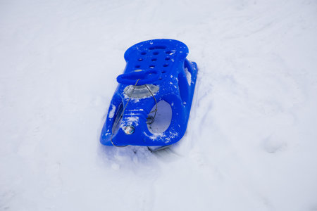 Blue sleigh stands on the background of white fluffy snow on a winter day. Winter atmosphere expressed by empty sleigh on the background of white snow. Enjoy speed and laughter in the cold season.の写真素材