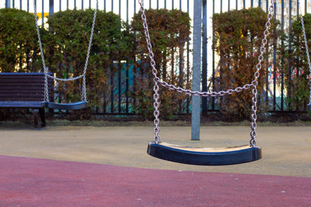 Empty swings on a playground evoke sadness and loneliness, metal chains gently swaying in the wind....