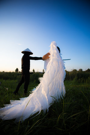 A samurai battles a winged angel against a natural backdrop at sunset, mixing fantasy and Asian influences in a gripping conflict between good and evil.の写真素材
