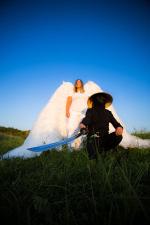 A ninja with a katana and an angel in a meadow at sunset, mixing spirituality and warrior strength in a surreal scene. Peace and power collide in a captivating image.の写真素材