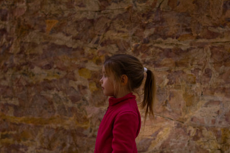 Young girl observing prehistoric cave paintings depicting animals and symbols, experiencing history and art during a museum visit, fostering curiosity and learning.の写真素材