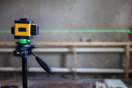 A laser level mounted on a tripod projects a green line onto a construction site. A laser level is essential for precise alignment and measurements in construction projects.の写真素材