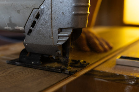 Laying laminate flooring in a house. A man cuts laminate planks with a jigsaw during the installation of new flooring, demonstrating the process of home improvement and DIY renovations.の写真素材