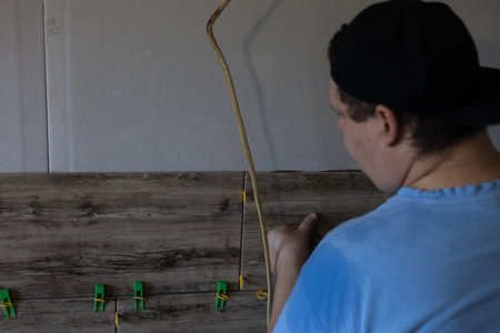 Man installing wood-effect ceramic tiles on a wall, meticulously adjusting their position during a...
