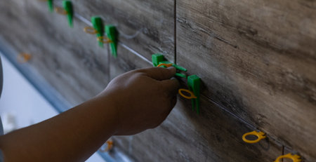 A man installs adjustable tile alignment clamps to ensure precise and consistent gaps between...