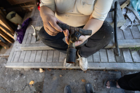 A man holds a complex section of rusty metal water pipe, demonstrating its components and wear,...