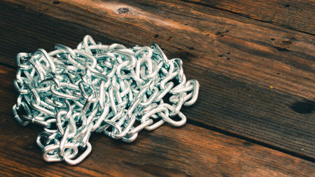 Metal shiny chain on a wooden surface close-up