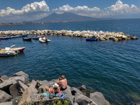 Sunbathers on the harbour in the Santa Lucia area of downtown Naples with a view over Mount Vesuvius in Naples, Italyのeditorial素材