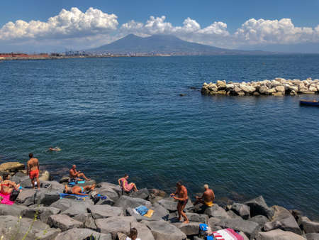 Sunbathers on the harbour in the Santa Lucia area of downtown Naples with a view over Mount Vesuvius in Naples, Italyのeditorial素材