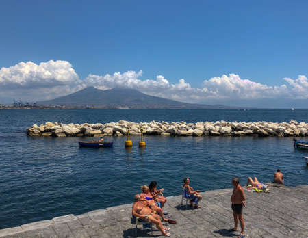 Sunbathers on the harbour in the Santa Lucia area of downtown Naples with a view over Mount Vesuvius in Naples, Italyのeditorial素材