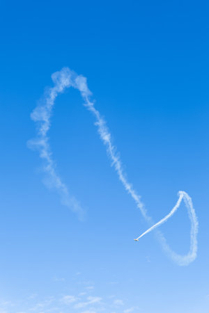 Airplane in the blue sky with white clouds, aerobatics