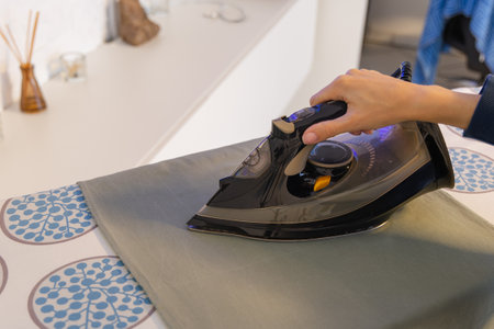 Close-up of woman ironing on board in bathroom at homeの写真素材