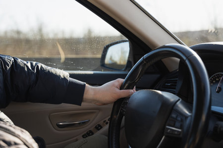 Man driving a car. Close-up of male hand on steering wheelの写真素材