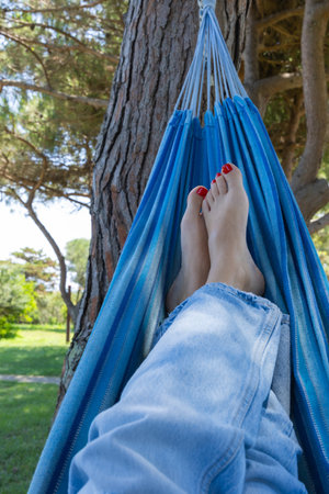 Female feet relaxing in a hammock in a park on a sunny dayの写真素材